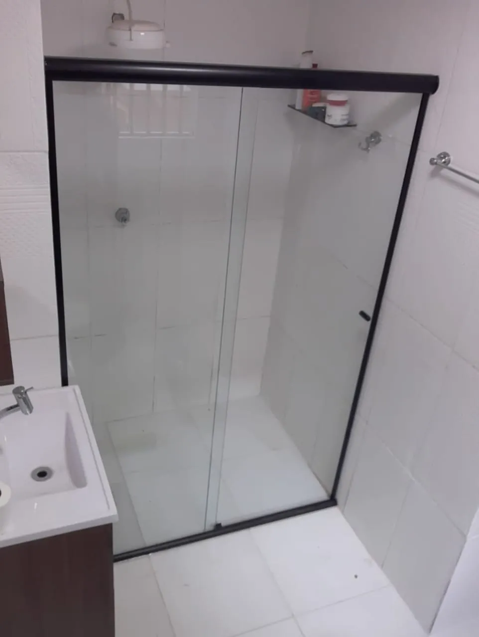 Box de vidro de correr com perfis pretos em banheiro de revestimento branco