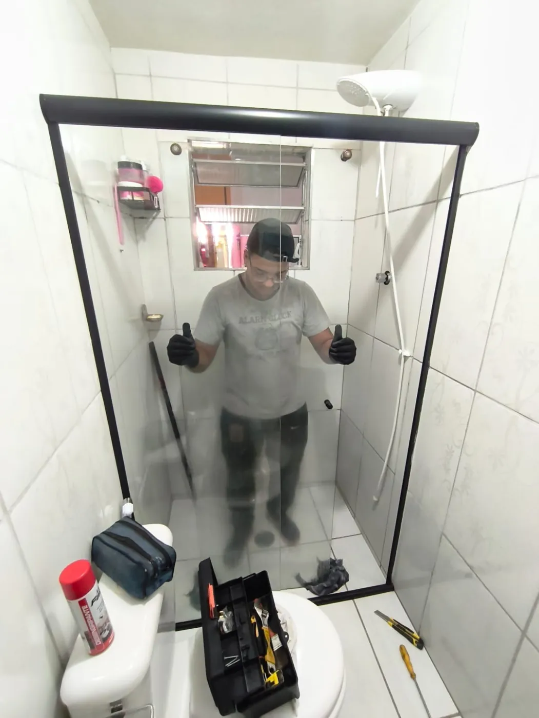 Profissional da Êxito dentro de box de vidro com perfil preto logo após a instalação