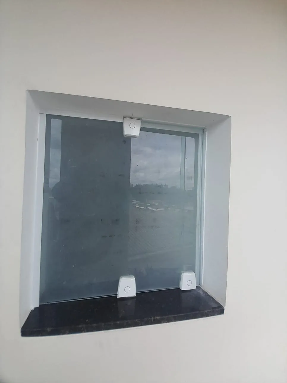 Janela de vidro instalada em vão com peitoril de granito escuro
