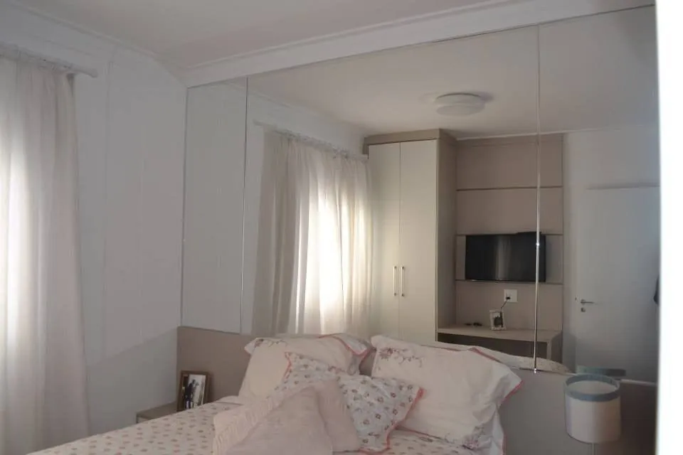 Espelho de parede atrás da cama em dormitório de tons claros