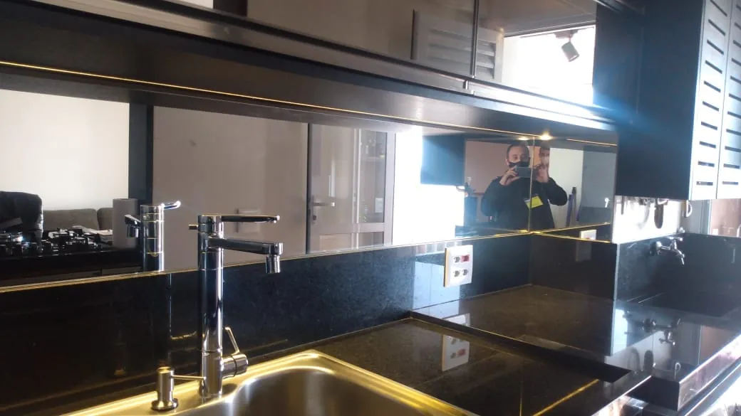 Espelho instalado acima da bancada de granito preto da cozinha